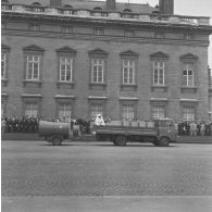 Défilé motorisé devant l'Ecole militaire. Passage d'un camion transportant des sapeurs de la brigade de sapeurs-pompiers de Paris (BSPP) en tenue de protection incendie et tractant un ventilateur, lors de la cérémonie du 14 juillet 1977.