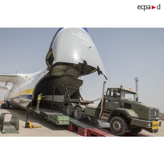 Déchargement d'une centrale d'enrobage à bitume tractée par un camion Renault CBH-380, depuis la soute d'un Antonov An 124-100 stationnant sur le tarmac de la Base aérienne 172 Fort-Lamy à N'Djamena.