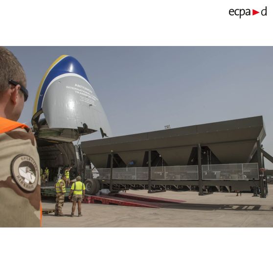 Déchargement d'une centrale d'enrobage à bitume tractée par un camion Renault CBH-380, depuis la soute d'un Antonov An 124-100 stationnant sur le tarmac de la Base aérienne 172 Fort-Lamy à N'Djamena.