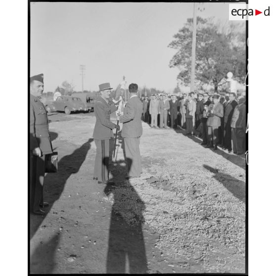 Le général Philippe Leclerc échange un drapeau avec une autorité civile, sous le regard d'autorités civiles et militaires.