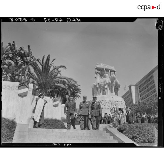 Plan en contre-plongée d'autorités civiles et militaires qui descendent les marches du monument aux morts d'Alger.