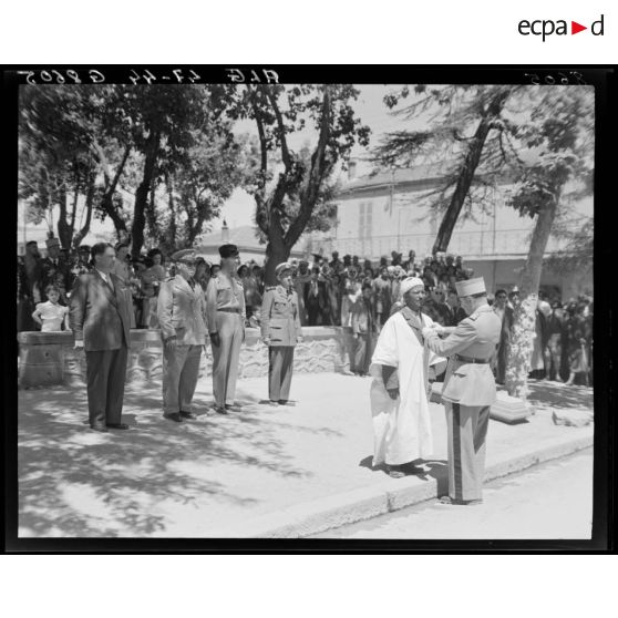 Le général Duché remet une décoraton à une autorité locale, sous le regard d'autorités militaires et de la population civile.