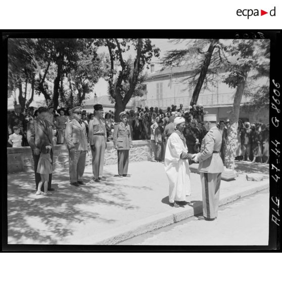 Le général Duché remet une décoraton à une autorité locale, sous le regard d'autorités militaires et de la population civile.