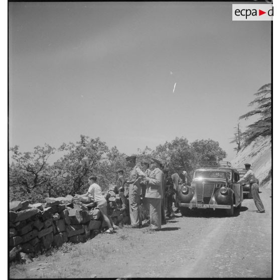 Le général Duché, accompagné de personnalités militaires, assiste à des scènes de folklore, depuis une route de montagne.