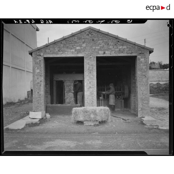 Des hommes préparent des bottes de foin dans un hangar à Maison-Carrée.