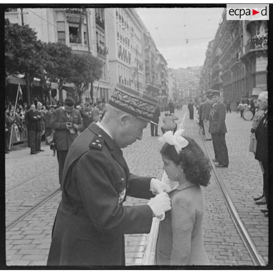 Le général Olleris remet une décoration à une fillette, lors de la cérémonie de commémoration du 11 novembre à Alger.