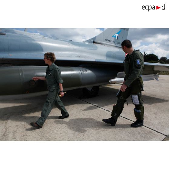 Le capitaine pilote de l'avion Mirage 2000-5 102-MK de l'EC (escadron de chasse) 1/2 Cigognes et le sergent féminin mécanicien de piste vecteur de l'ESTA (escadron de soutien technique aéronautique) 2E Chalosse de la BA 118 effectuent le tour de contrôle avant le départ en mission.