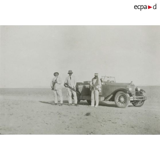 [Portrait de chasseurs près d'une automobile dans un désert].