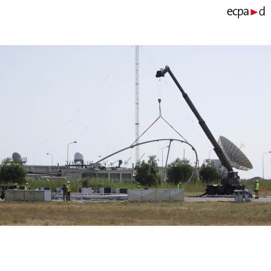 Aménagement d'une nouvelle zone pour accueillir un drone par les techniciens de l'armée de l'Air, sur la base aérienne de Sigonella. Levage d'un élément structurel de hangar par une grue Manitou.