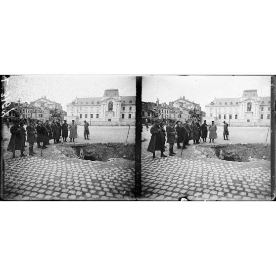 Reims. Visite d'une mission canadienne. La mission Place du Parvis, au 1er plan : trou d'obus. [légende d'origine]