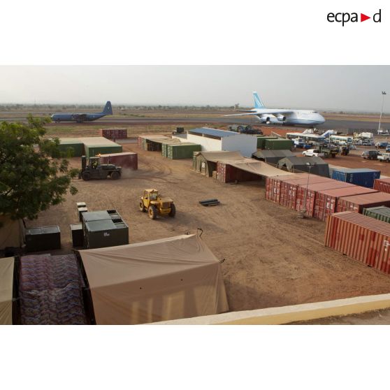 Derrière une zone de regroupement logistique, un avion-cargo de transport Antonov 124-100 ukrainien stationne sur une piste de l'aéroport de Bamako, pendant le roulage d'un Hercules C-130 de l'armée nigériane.