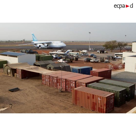 Derrière une zone de regroupement logistique, un avion-cargo de transport Antonov 124-100 ukrainien stationne sur une piste de l'aéroport de Bamako.