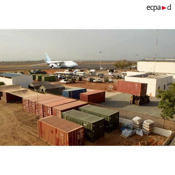 Derrière une zone de regroupement logistique, un avion-cargo de transport Antonov 124-100 ukrainien stationne sur une piste de l'aéroport de Bamako.