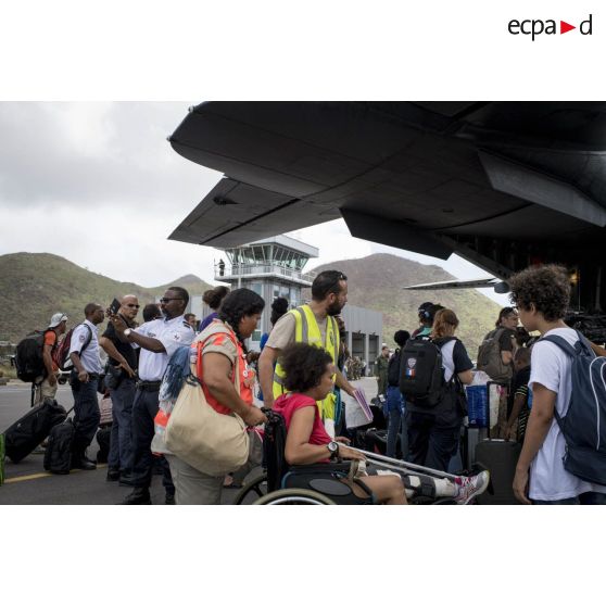 Un personnel de la base aérienne 367 de Cayenne prend en charge une personne à mobilité réduite pour son évacuation à bord d'un avion Casa Cn-235 à Grande Case sur l'île de Saint-Martin, aux Antilles.