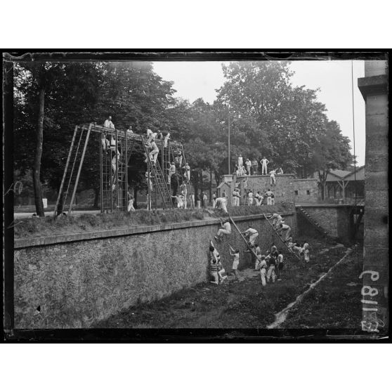 Joinville-le-Pont (Seine). Ecole normale militaire de gymnastique. L'escalade d'un mur et la montée aux échelles. [légende d'origine]