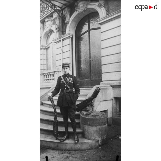 Un officier pose devant l'entrée d'un bâtiment. [légende d'origine]