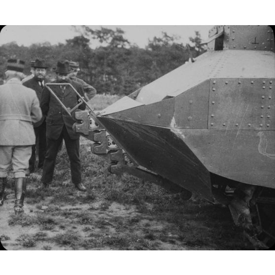 [Détail d'un système de coupe de barbelés installé à l'avant d'un engin blindé en essai devant plusieurs autorités dont Albert Thomas.]