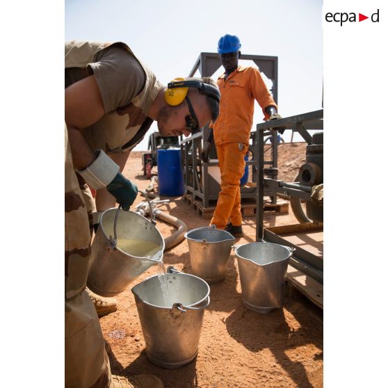 Un soldat du Service des essences des armées (SEA) transvase du carburéacteur dans des seaux sur le dépôt militaire de Niamey, au Niger.