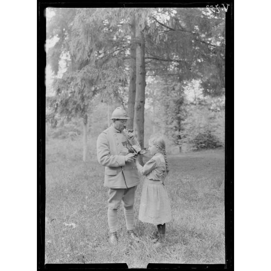 Petite fille offrant à un soldat un bouquet de muguet. [légende d'origine]