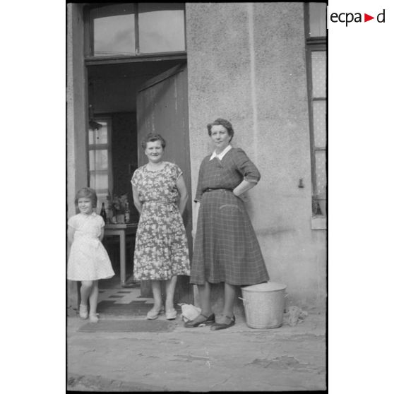 Dans le nord, portrait de la famille Smet. Portrait de deux femmes et d'une jeune fille sur le pas de porte. [légende d'origine]