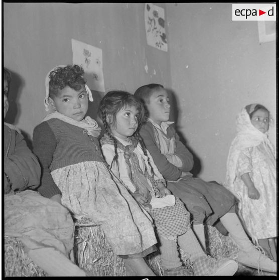 Aménagement de l'eau dans le secteur de Tamesna sous le commandement du capitaine Vinck. Dans une salle de classe, portrait de jeunes enfants assis sur des ballots de foin qui tiennent lieu de bancs d'école. [légende d'origine]