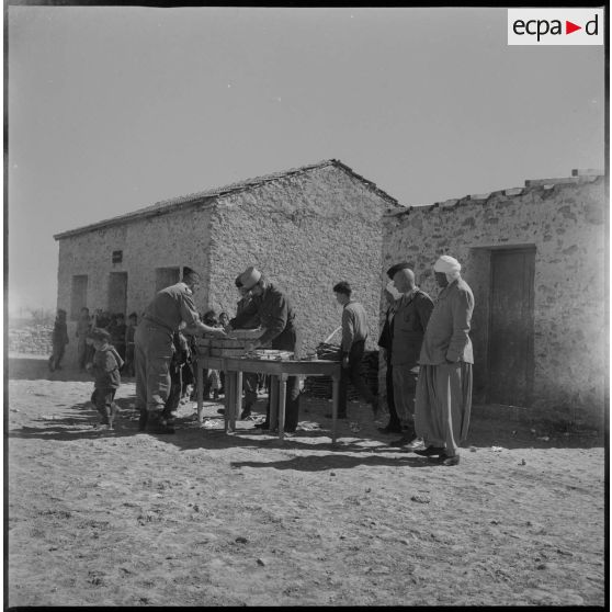 Des soldats effectuent une distribution auprès des enfants du village. [légende d'origine]