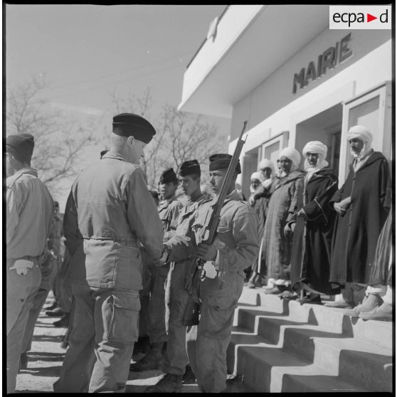 Après lui avoir remis un fusil, un officier salue un membre du nouveau maghzen (ou groupe d'autodéfense) du village de Wagram. [légende d'origine]