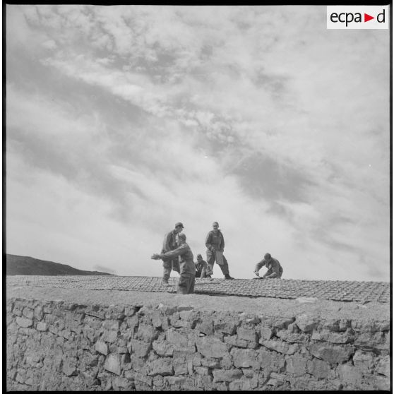 Des soldats travaillent à la réalisation d'une toiture. [légende d'origine]