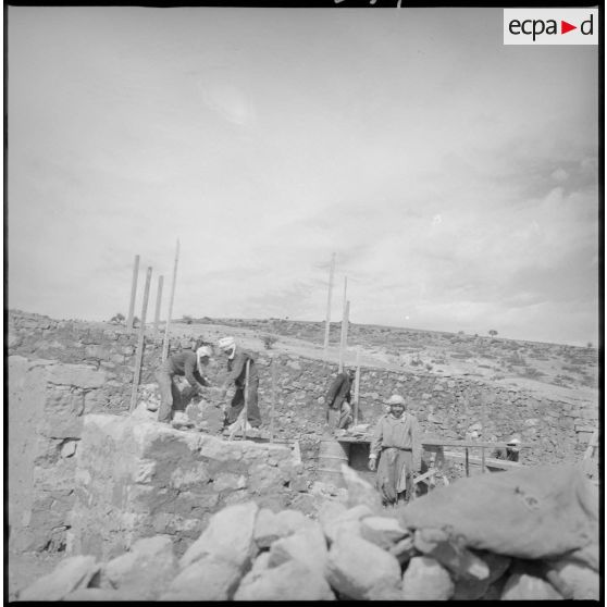 Ouvriers au travail sur un chantier de construction. Travaux de maçonnerie. [légende d'origine]