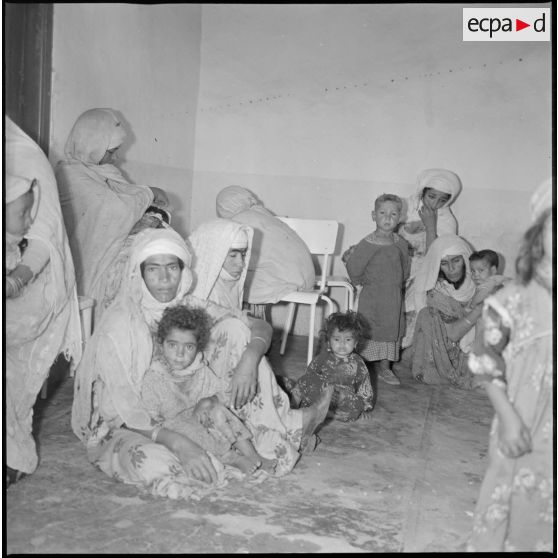 Portrait d'un groupe de femmes et d'enfants assis dans une salle d'attente. [légende d'origine]