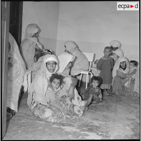 Portrait d'un groupe de femmes et d'enfants assis dans une salle d'attente. [légende d'origine]