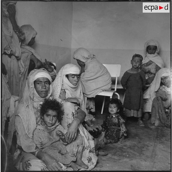 Portrait d'un groupe de femmes et d'enfants assis dans une salle d'attente. [légende d'origine]