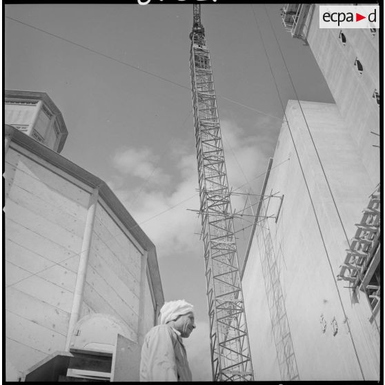 [Vue en contre-plongée d'un homme devant un silo, une grue et un bâtiment en construction sur les docks coopératifs de Saïda.]