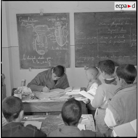 [Instituteur d'une SAS corrigeant les cahiers des écoliers, dans l'école du centre de Saïda.]