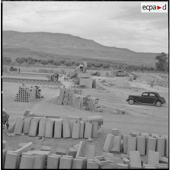 [Vue sur des matériaux de construction entreposés sur un terrain. Ils sont utilisés pour la construction des nouvelles bâtisses du centre de regroupement de la ferme Cazorla.]