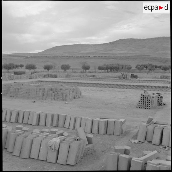 [Vue sur des matériaux de construction entreposés sur un terrain. Ils sont utilisés pour la construction des nouvelles bâtisses du centre de regroupement de la ferme Cazorla.]