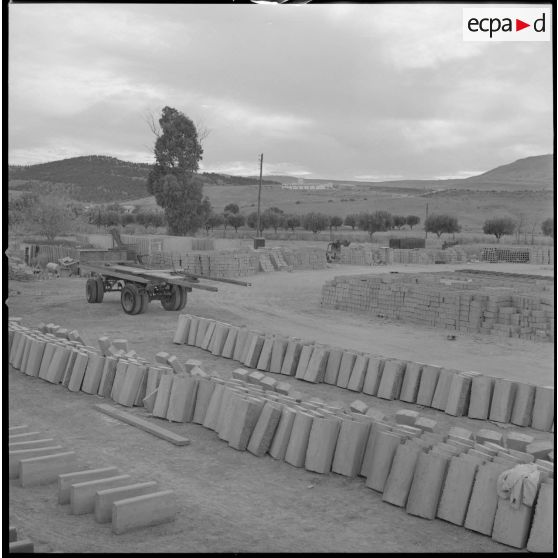 [Vue sur des matériaux de construction entreposés sur un terrain. Ils sont utilisés pour la construction des nouvelles bâtisses du centre de regroupement de la ferme Cazorla.]