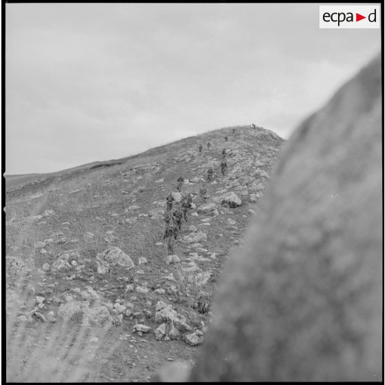 [Colonne de soldats du 2/8e RIM en progression dans une zone escarpée au cours d'une opération en Kabylie.]