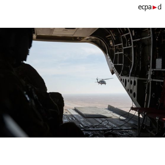 Porte de la soute d'un hélicoptère CH-47 Chinook américain transportant les bigors du contingent du 3e RAMa en transit depuis Al-Asad Air Basa vers Al-Qaïm en Irak. Ce dernier est escorté par un UH-60L Blackhawk.