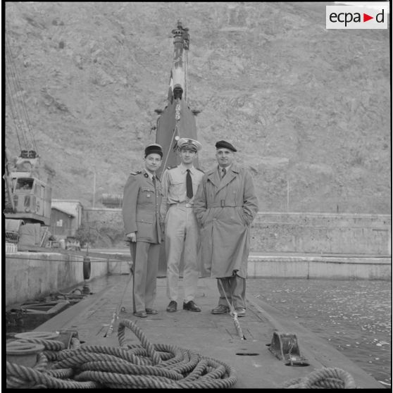 [Commandant, officier de la Marine et aumônier militaire posant dans le port d'Oran.]