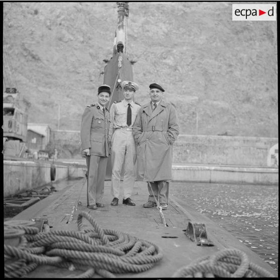 [Commandant, officier de la Marine et aumônier militaire posant dans le port d'Oran.]