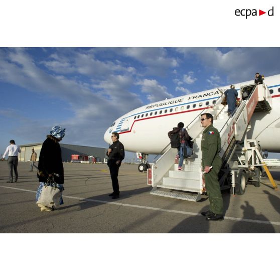 Embarquement de ressortissants évacués par la passerelle de l'Airbus A340 de l'escadron de transport 3/60 Esterel sur l'aéroport de Tripoli (Libye), sous le regard d'un capitaine membre de l'équipage et d'un agent du ministère des Affaires étrangères.