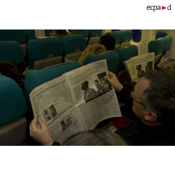 Un ressortissant évacué de Tripoli (Libye) lit un article sur "La légion africaine de Kadhafi" dans journal "Le Monde" dans l'avion Airbus A340 de l'escadron de transport 3/60 Esterel.