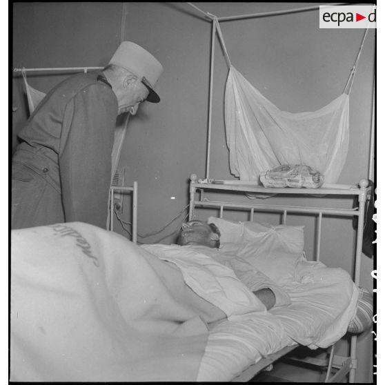 Le général de Linarès au-dessus du lit d'un soldat alité à l'hôpital Lanessan à Hanoï.