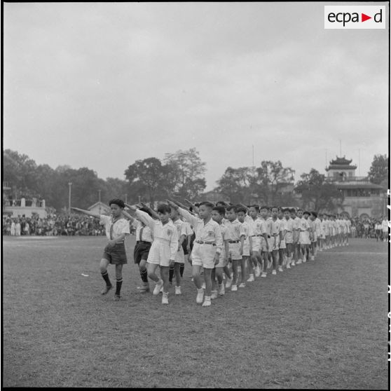 Défilé de jeunes athlètes des écoles chrétiennes faisant le salut olympique lors d'une grande réunion des élèves catholiques au stade Mangin.