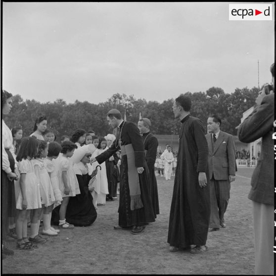 Une sœur des écoles chrétiennes de Hanoï baise l'anneau papale de Mgr Dooley lors d'une grande réunion des élèves catholiques au stade Mangin.