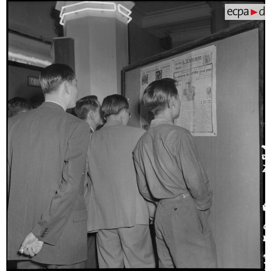 Groupe de civils devant un panneau d'information annonçant la mort du maréchal de Lattre de Tassigny dans un hall du Service d'information.