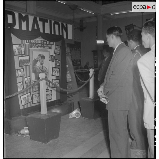 Civils et militaires devant un panneau d'information annonçant la mort du maréchal de Lattre de Tassigny dans un hall du Service d'information.