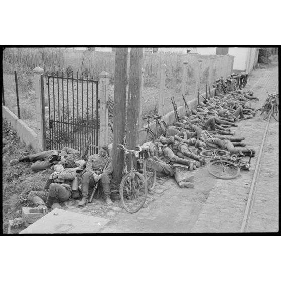 En Belgique, entre Mons et Valenciennes et à quelques kilomètres de Thulin, des cyclistes allemands prennent du repos dans la rue de Villiers à Hensies.