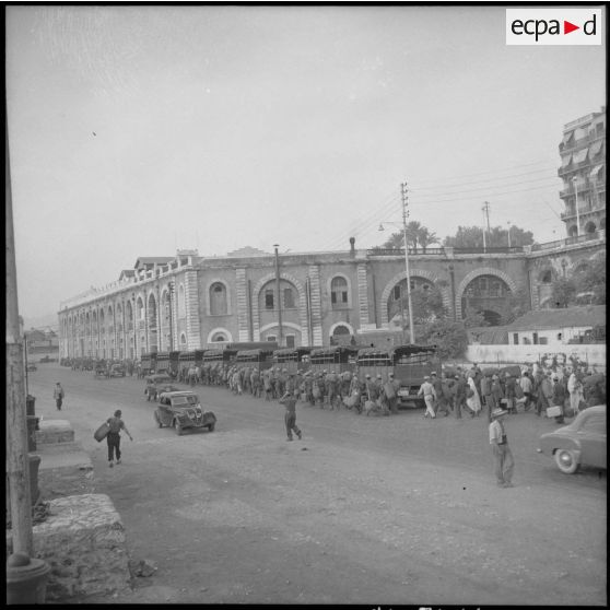 Colonne de militaires progressant devant un bâtiment militaire dans la région d'Alger.